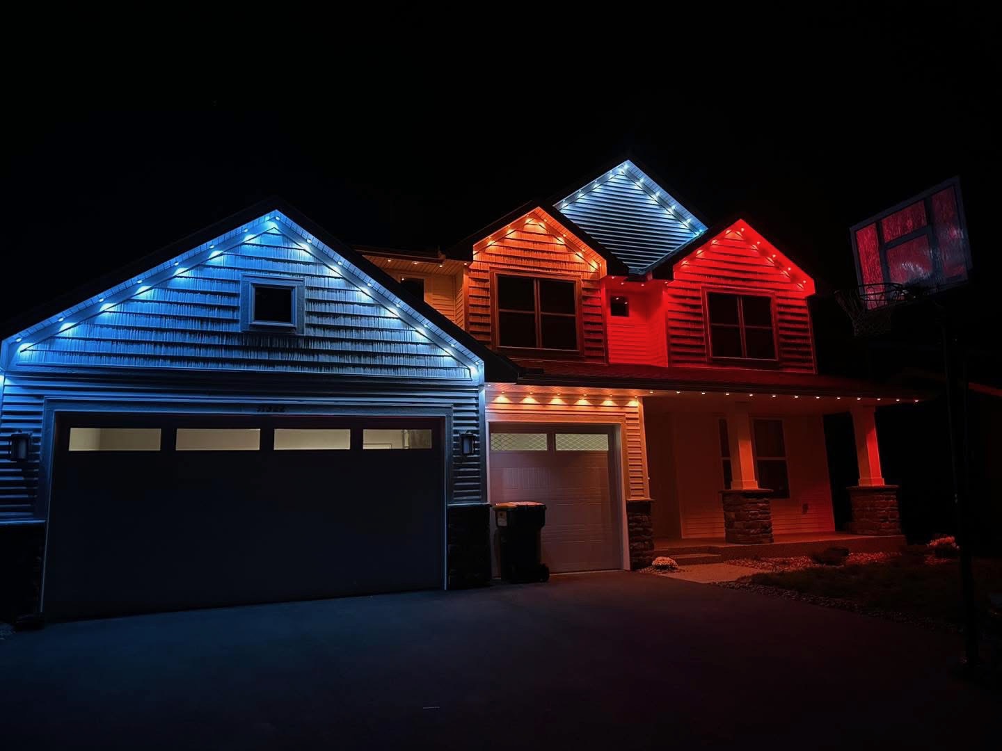 Craftsman home with blue and red lit gables and warm white accents