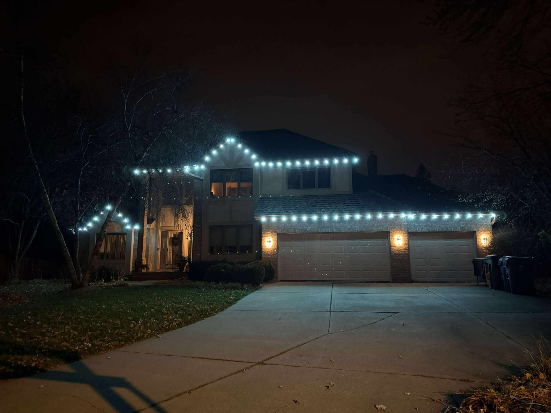Home with warm white permanent lighting across the roofline at night